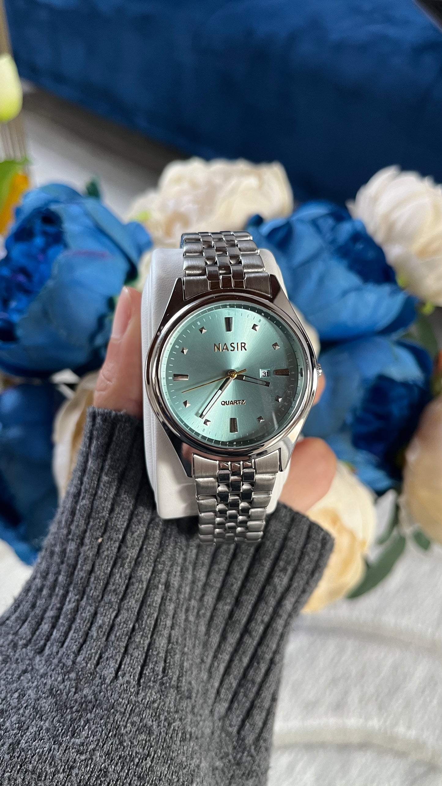 Montre Baby Blue unisexe avec cadran bleu rond et bracelet argenté en acier inoxydable sur fond de fleurs